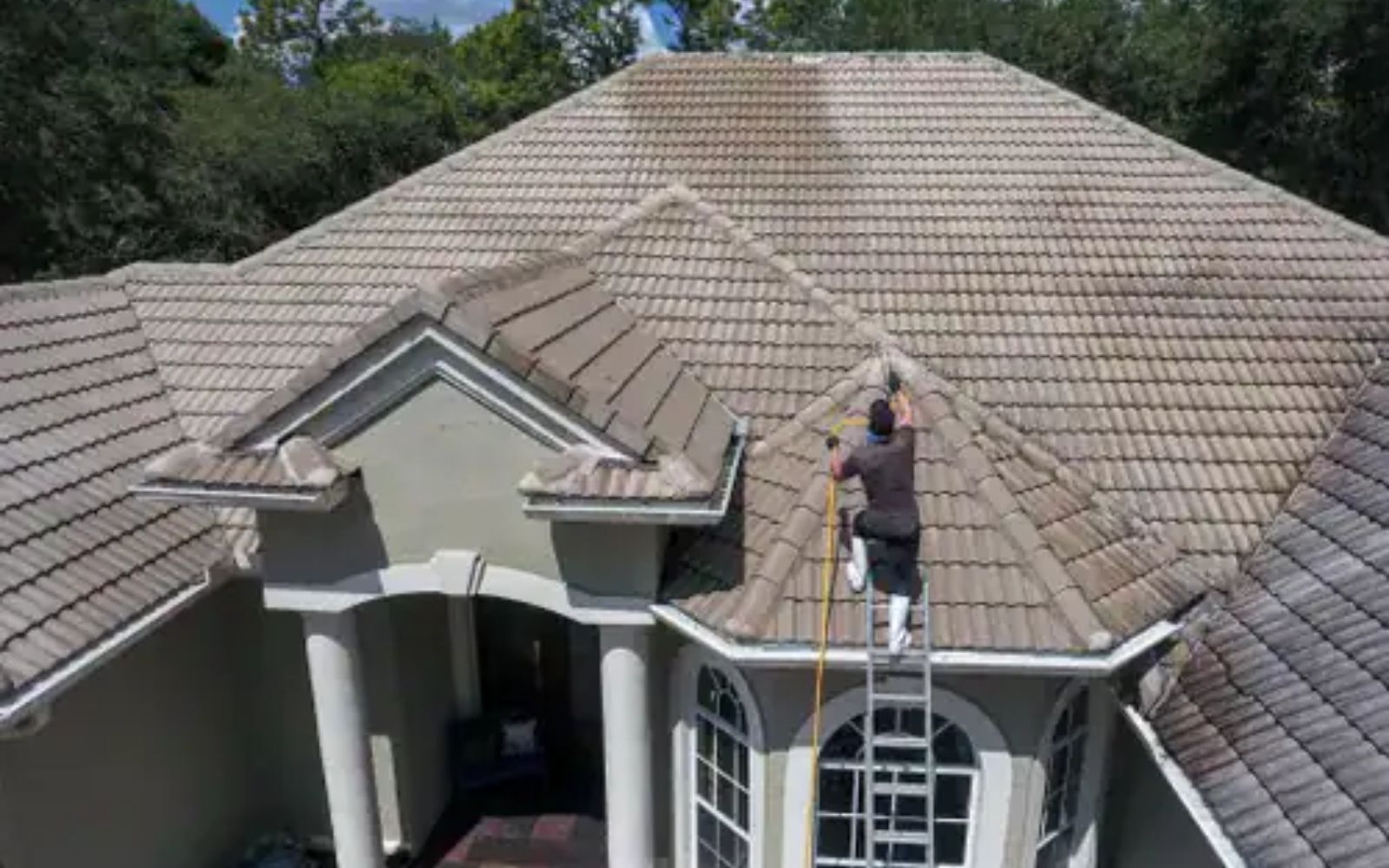 Our team soft washing a luxury home roof